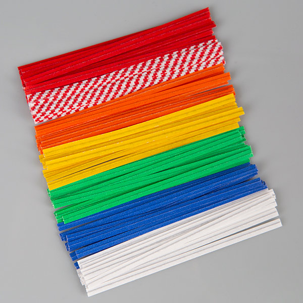 A stack of colorful Bedford twist ties arranged in rows on a gray background. The twist ties are grouped by color, including red, red-and-white checkered, orange, yellow, green, blue, and white. Each tie is uniform in length, highlighting the variety of color options available for packaging use.